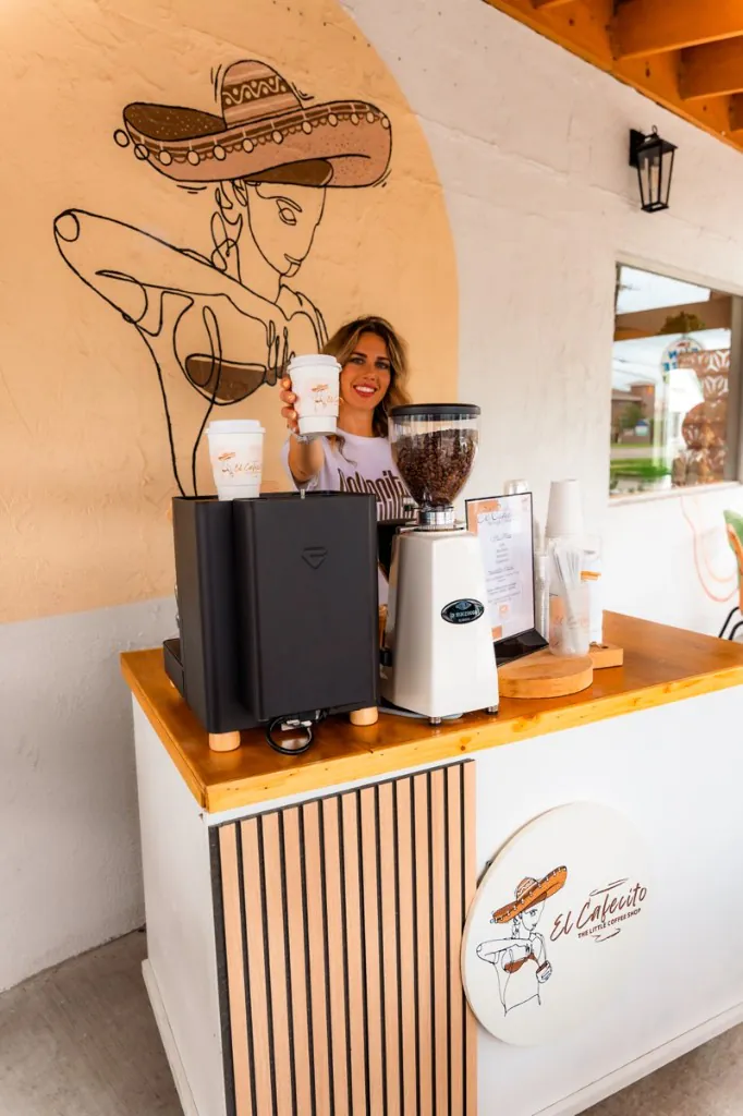 Barista serving coffee from the El Cafecito catering cart